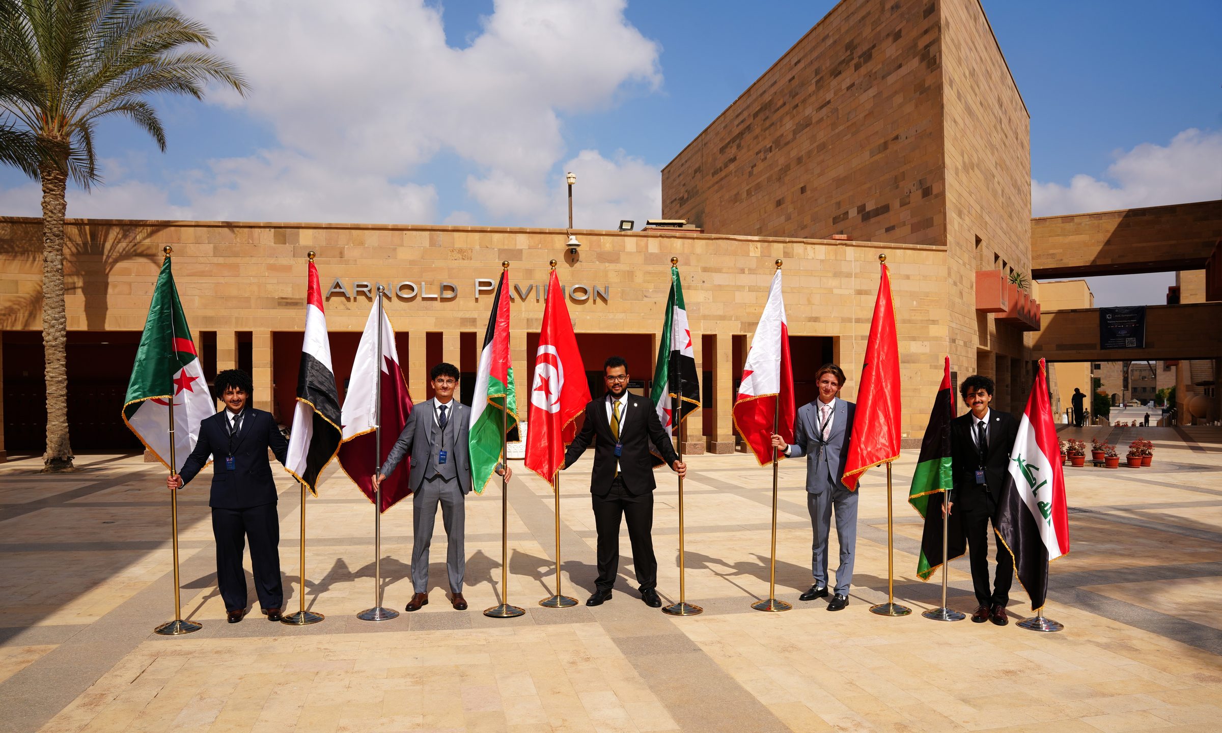 Scholars holding the flags of their countries in front of Arnold Pavilion at AUC