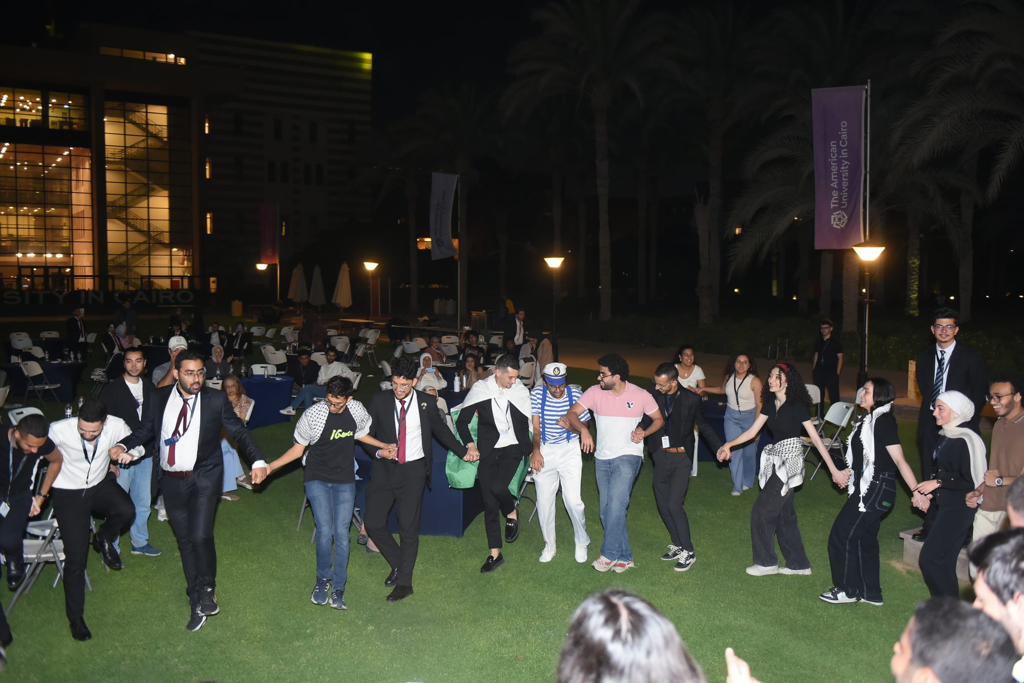 Delegates joining a dabke on the campus lawn at night
